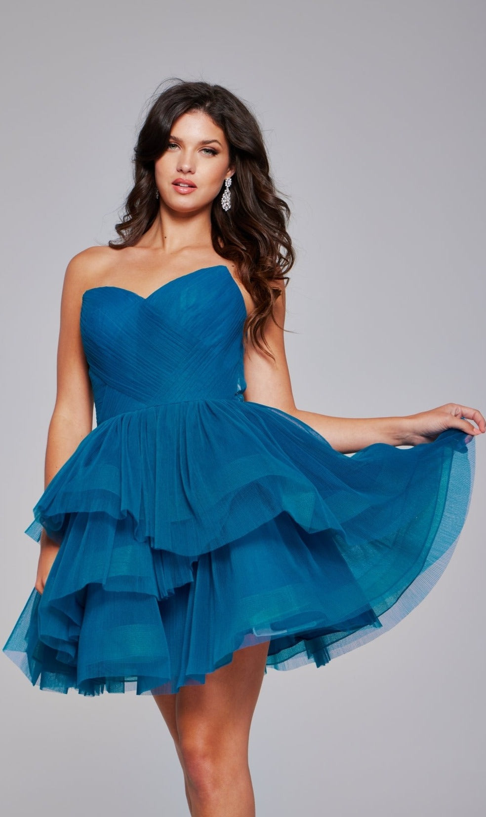 A woman models the Jovani Strapless Short Babydoll Hoco Dress 41054, featuring a sweetheart neckline and babydoll skirt, while posing against a plain gray background.